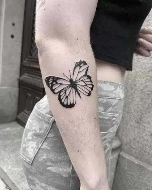 Blackwork butterfly tattoo on an inner arm
