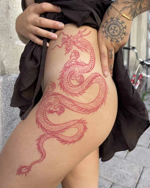 Fine line red dragon tattoo on a hip