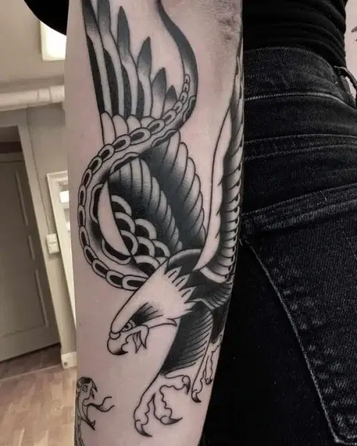 Traditional black and grey eagle and snake on an upper arm