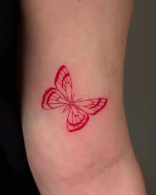 Fine line red butterfly tattoo on an inner arm
