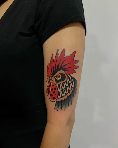 Traditionell tatuering av en tupp på ett ben