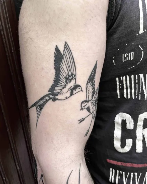 Traditional tattoo of two swallows on an upper arm